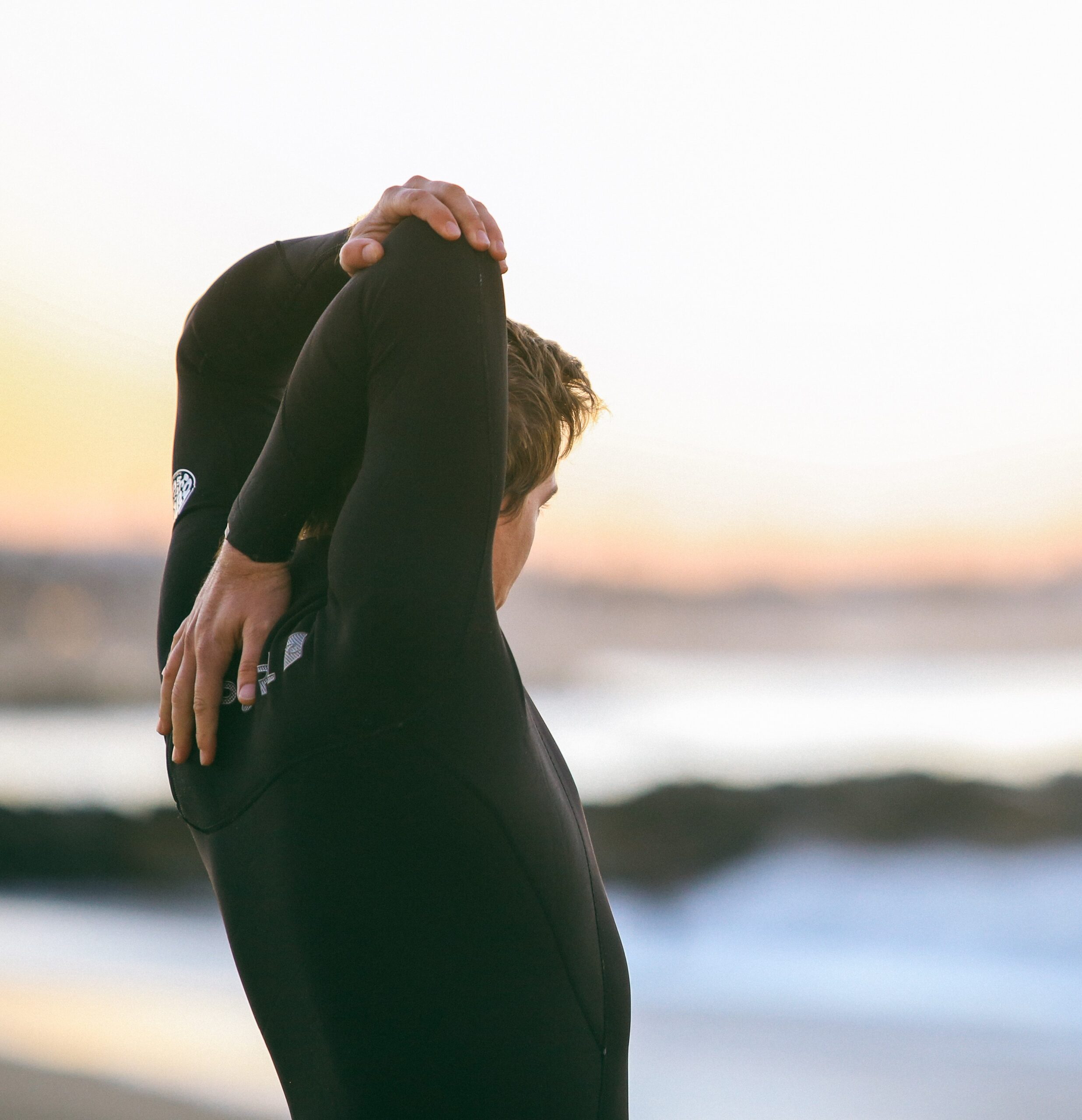 Man-Overlooking-A-Beach-In-A-Wetsuit